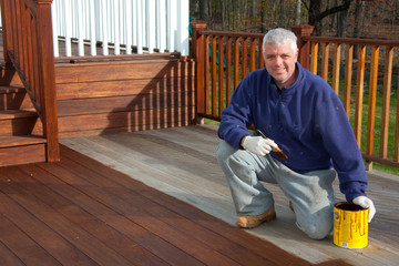 man staining deck on a house