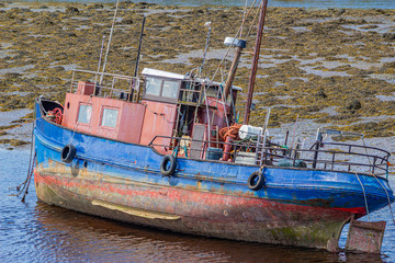 Fototapeta na wymiar Old fishing boat in Clifden Bay at low tide, sunny spring day in the province of Connacht, Ireland
