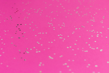 Silver sparkles on pink trendy background. Festive backdrop for projects. Flat lay style. Top view. Selective focus