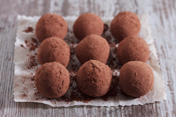 Handmade energy balls in cocoa on white paper on the table. Homemade healthy sweets. Concept: healthy eating.