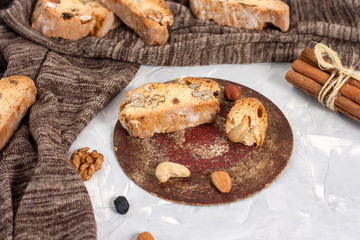 Tasty traditional Italian homemade biscotti or cantuccini cookies with hazelnuts, almonds and walnuts on a light gray background.
