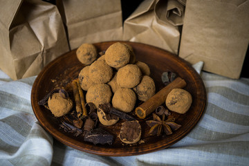 Handmade chocolate truffles on vintage clay plate with fragrant spices on dark background