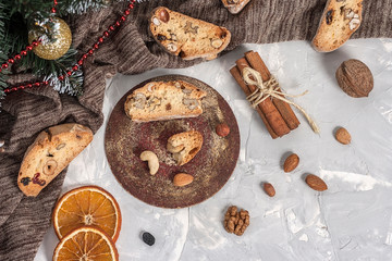 Fototapeta na wymiar Traditional Italian biscotti or Cantuccini cookies with hazelnuts, almonds, walnuts on a gray background with slices of dried oranges and cinnamon. Top view