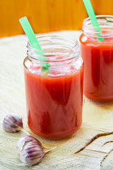 jars with tomato juice stands on a wooden cut