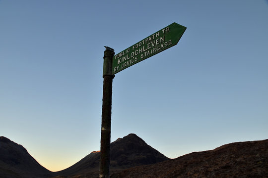 Signpost for public footpath to Kinlochleven via the Devil's Staircase. This is part of the famous West Highland Way long distance walking route. Taken at sunrise with mountain backdrop.