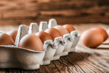 Eggs in basket. Brown chicken egges on wooden vintage table. Fresh egg on morning breakfast.