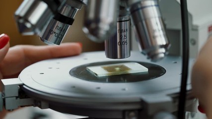 Geological rock sample on the slide glass under the light microscope lens. Rotation of microscope adjustment platform. Close up.