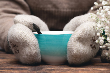 Woman in warm sweater and mittens is drinking a hot tea close up background.