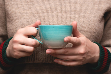 Woman in warm sweater drinking a hot tea close up background.