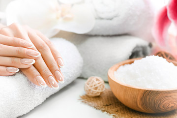 Obraz na płótnie Canvas Woman beautiful hands with precise french manicure. Nails care and spa treatment or procedure. Relaxing concept with salt in olive bowl.
