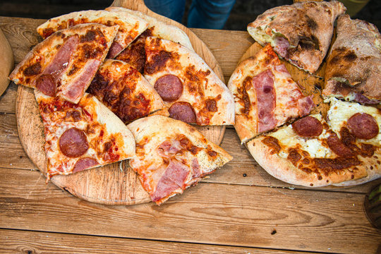 Hot sliced crunchy pepperoni, bacon, tomato, cheese pitsa on counter for sale.