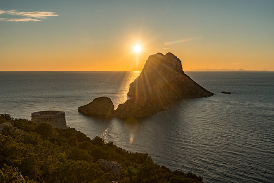 Stunning views of the sun falling behind Es Vedra with the Torre del Savinar in Es Vedra, Sant Josep de Sa Talaia, Ibiza, Spain.