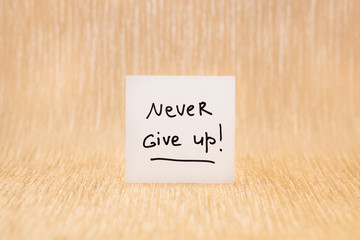Never give up - card with lettering on glitter gold background, motivation phrase