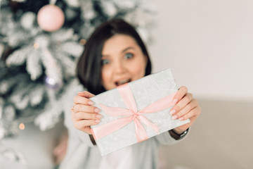 christmas, x-mas, winter, happiness concept - smiling woman with many gift boxes. background of the Christmas tree. happy young woman celebrating Christmas