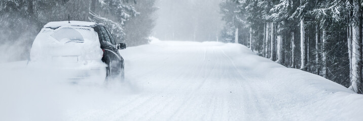 Winter road in beatiful frosty forest. Snow calamity or blizzard on street. Fast cars on snowy roads in storm.