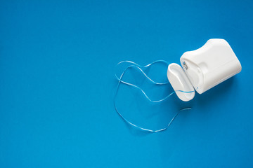 dental floss  on a blue background, the concept of care for the oral cavity, preventing tooth decay