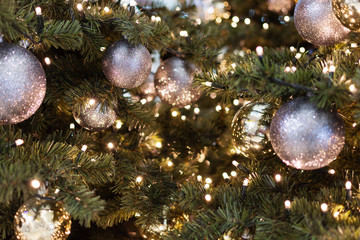 Obraz na płótnie Canvas Decorated Christmas tree closeup. Golden, black and silver balls and garland with lights. New Year photo with bokeh. Winter holiday light decoration.