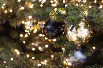Decorated Christmas tree closeup. Golden, black and silver balls and garland with lights. New Year photo with bokeh. Winter holiday light decoration.