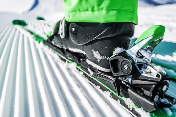New groomed piste or slope. Lines in snow. Winter skis and detailed view of the ski bindings...
