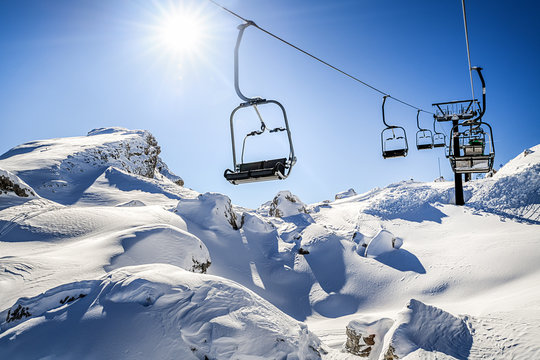 Ski lift in the dolomity mountains. Seats of skis resort on steel ropes in sunny winter day. Cinque torri location.