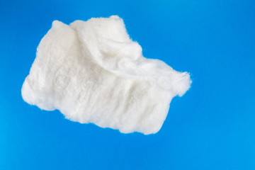 large roll of medical cotton on blue background close-up