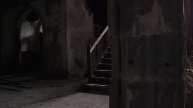 CLOSE UP: Dark entrance area with arch ceiling in antique stone-build abandoned cathedral. Weathered broken wooden staircase leading into the bell tower. Spooky old church falling into disrepair