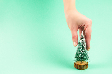 Small christmas tree in woman hand on a green background.