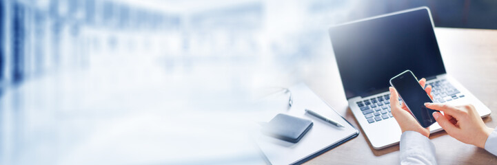 Business hands working on smatphone with laptop blank background. Modern design notebook,  copy space. Computer keyboard typing mockup wide banner.