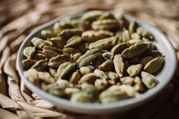 Heap of cardamom seeds in a bowl. Close up view of cardamom seeds as background for design. Organic and healthy food.