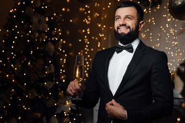 Mature successful handsome man in classic suit, waiting for the New Year holiday. Bearded man in gray classic suit having luxury style. Winter holidays celebration concept