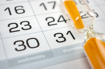 hourglass on the background of the calendar for the month, end of the month, deadline, reports,...