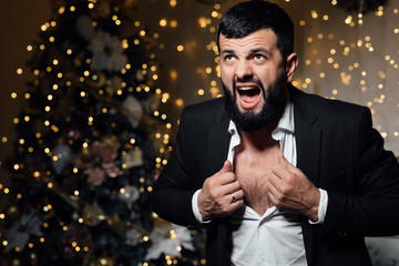 Handsome new year man with beard. Man tearing at his shirt. Happy sexy man  in classic suit, can not wait for the celebration for the New Year holiday.