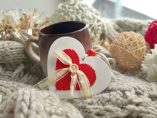 Fototapeta na wymiar Close up coffee mug with decorated heart on knitted scarf. Nordic Christmas greeting card.