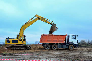 Excavator load the sand to the heavy dump truck on construction site. Excavators and dozers digs the ground for the foundation and construction of a new building. Apartment renovation program