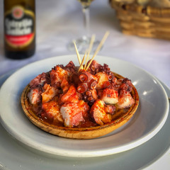 Octopus in spicy sauce in plate, spanish style closeup.