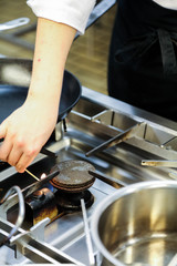 Hand lighting gas on stove in professional kitchen