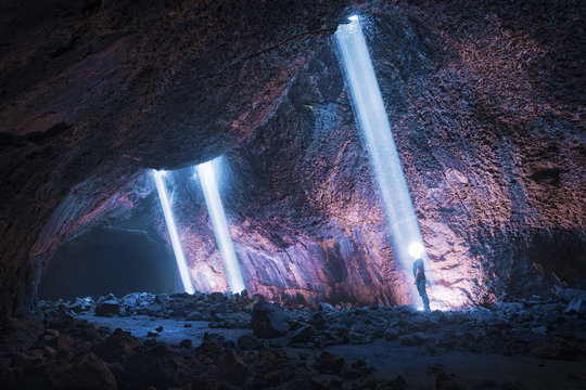 volcanic cave with person standing in light beam