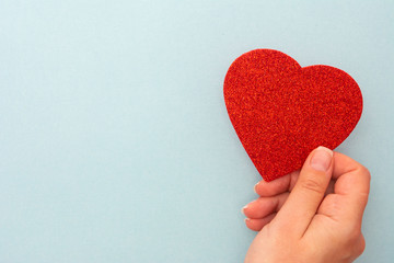 Valentine's Day background. Woman holding red heart on blue background, top view with copy space.