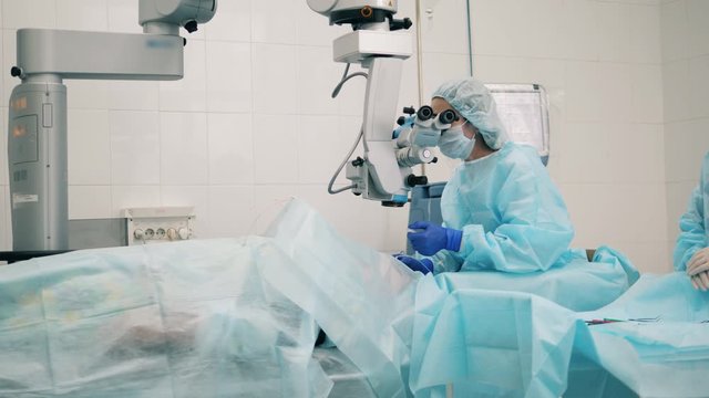 Ophtolmologist in eye hospital. Female doctor is operating with an eyesight medical machine