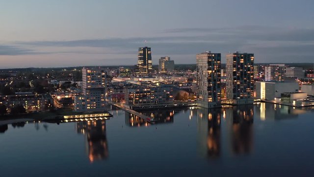 Aerial view of Almere city center with its modern architecture and highrise business and residential buildings, illuminated at dusk