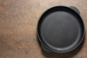 Flat lay overhead of black empty plate or pan on brown rustic stone background with copy space for your design. Minimalism style composition. Table setting.