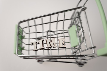 shopping cart with the inscription time lined with letters, the concept of a for a limited and valuable time, money can not buy the time