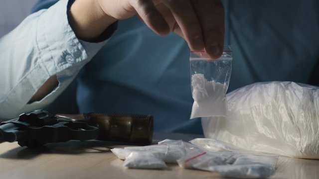 Drug dealer holding a dose of cocaine or heroin in his hands, close-up