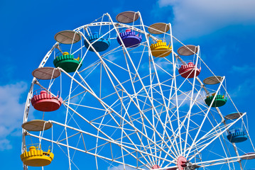Big wheel with multicolored cabins in amusement park 