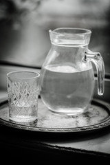 Jug of water and a glass on the windowsill, black and white photo.