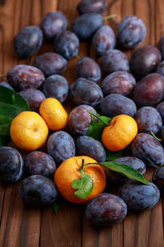 fresh mandarines and plums on wooden background