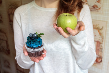 green apple and sugar cupcake in the hands, the dilemma of what to choose, the concept of healthy...