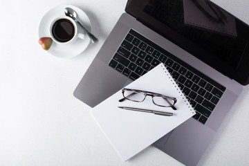 Workspace with laptop, notepad, tablet, glasses, cup of black coffee on a white background