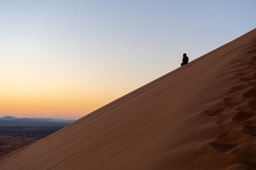 Fototapeta na wymiar Man on the slope of Sand dune of Erg Chebbi in the Sahara Desert, Morocco
