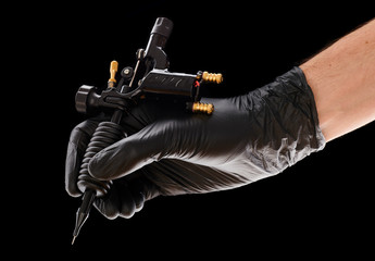Tattoo machine in artist's hand isolated on black background